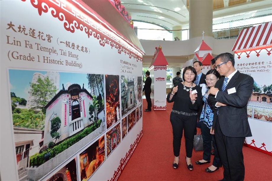 Mr Chan (right) listens to an introduction on several historic churches and temples at the photo exhibition.