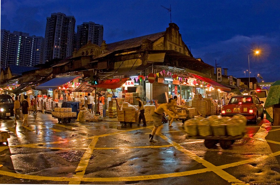 Open Category - Champion<br>Wong Chi Keung<br>Building: Yau Ma Tei Wholesale Fruit Market<br>Grading: Grade III<br>Artist's statement: 不一樣的天空 - 「油麻地果欄」群建築獨特，每朝天未亮從業員便辛勤工作，為繁華的香港付出努力。<br>Comments by the Jury Members: 這張照片拍攝時正值工人辛勤工作，捕捉的時間恰好，曝光很準，構圖和線條很美。前面的人推著貨物，代表一個保存到現在的古老行業，而後面那麼高的新式樓宇，和果欄對比著。都市繁華，有賴人們默默耕耘，帶出正面訊息，活現古蹟。拍攝時剛下過雨，令相片的色彩和光影更豐富。